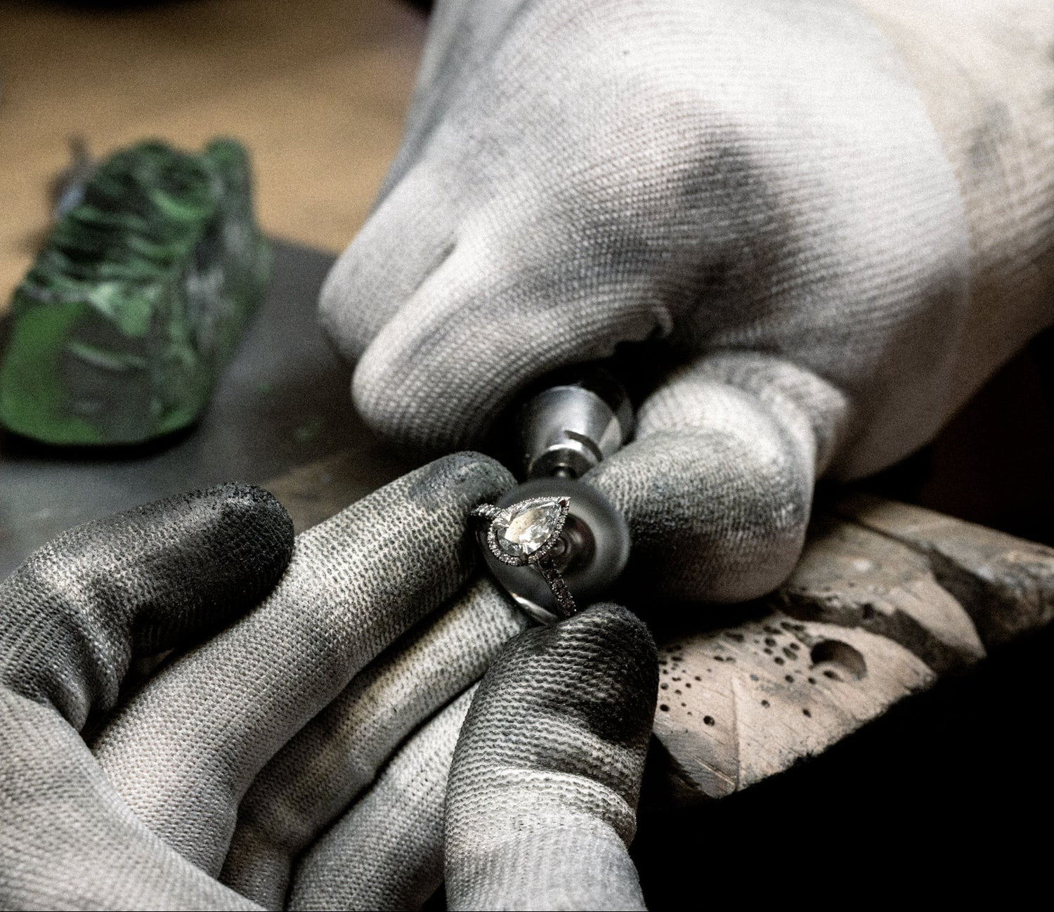 Goldschmied mit Handschuhen beim Finishing eines Diamantrings – präzises Polieren und Oberflächenbearbeitung bei Precious Metal Casting AG (PMC).