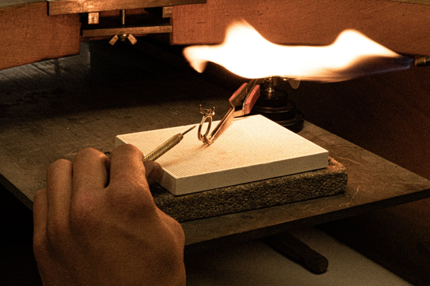 Goldschmied beim Löten eines Ringes mit offener Flamme – präzise Handarbeit im Finishing bei Precious Metal Casting AG (PMC).