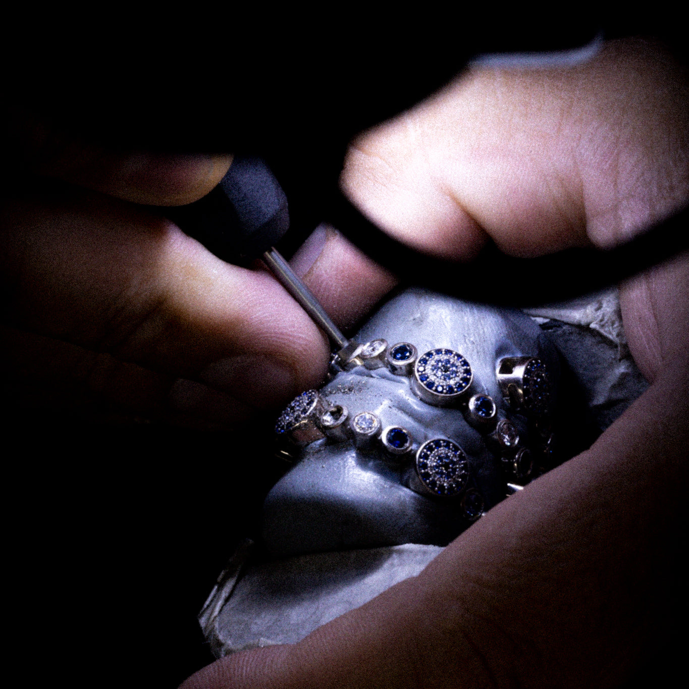 Goldschmied bei präziser Handarbeit an Ringen mit blauen Edelsteinen – Feinstbearbeitung und Finishing bei Precious Metal Casting AG (PMC).